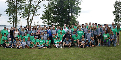 Image of approximately 60 happy people at an outdoor family reunion